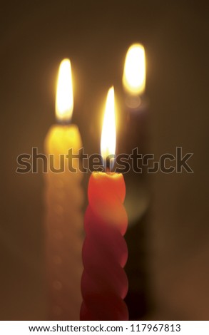 Three candles of red, yellow, and black with the light on