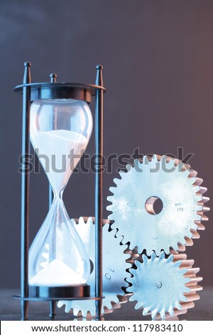 a sand clock with white sand in it and three gears placed together