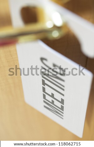 zoomed and focussed image of meeting sign on a golden door handle