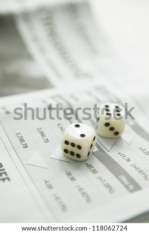 two die sitting on a stock market section page of a newspaper