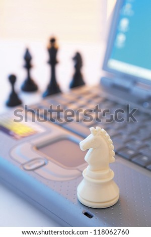 Still life with white knight chess piece on laptop