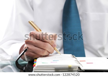 Close-up of a man in formal wear writing in his calendar