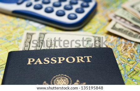 Close up shot of a US passport with US currency and a calculator, with a map for a background.
