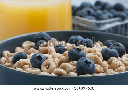 Breakfast cereal with blueberries and a glass of orange juice.