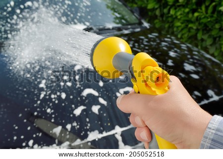 Car care - Woman using a garden spray gun to remove the soap