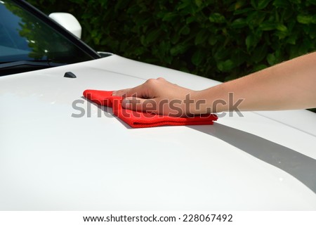 Car care - Car polishing - Polishing a white car with a red cloth.