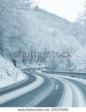 Winter Driving - Curvy Snowy Country Road - Curvy snowy country road leading through a mountain landscape.