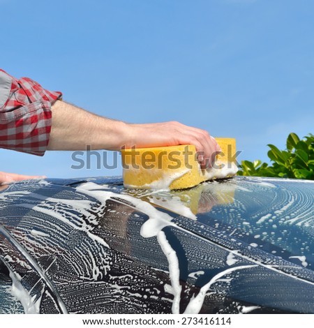 Car Care - Man washing a car by hand using a sponge