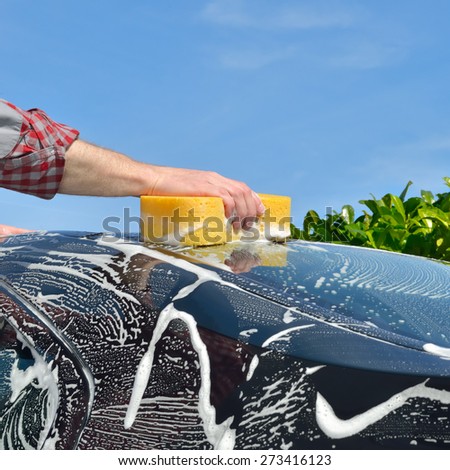 Car Care - Man washing a car by hand using a sponge