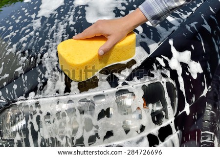 Car Care - Woman washing a car by hand using a sponge