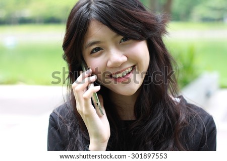 Portrait of thai student teen beautiful girl Answer the phone and smile.