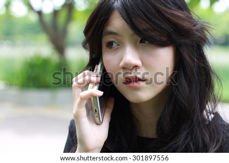Portrait of thai student teen beautiful girl Answer the phone and smile.