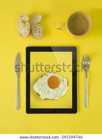 technology addiction concept: hipster breakfast with egg picture tablet device, coffee and bread in yellow style