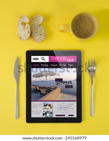technology wireless concept: hipster breakfast with tablet device with trends blog on the screen, coffee and bread in yellow style