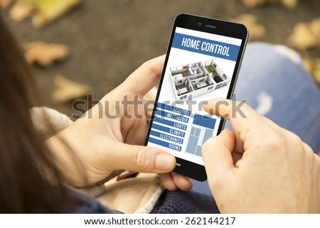 home automation concept: young woman with smart home control app at the park