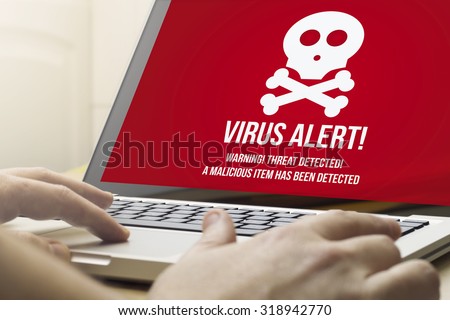 security concept: man using a laptop with virus alert on the screen. Screen graphics are made up.