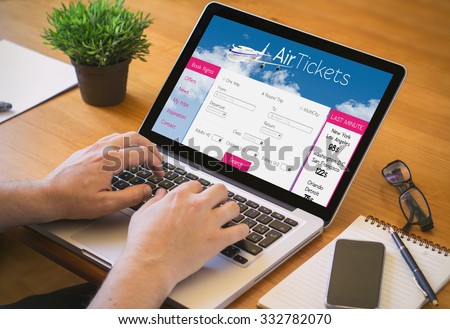 Close-up top view of man working on laptop with tickets flights web. all screen graphics are made up.