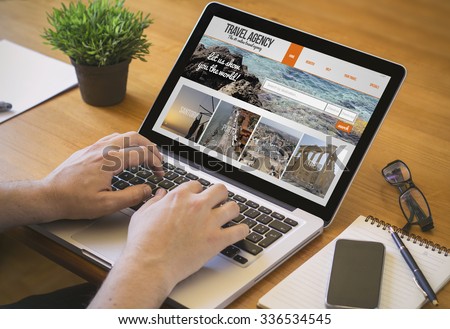 Businessman at work. Close-up top view of man working on laptop withtravel agency website on screene. all screen graphics are made up.
