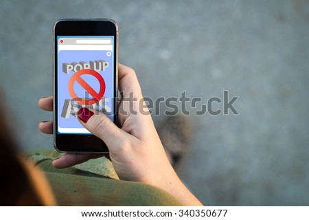 Top view of woman walking in the street using her mobile phone with ads blocker on the screen with copy space. All screen graphics are made up.