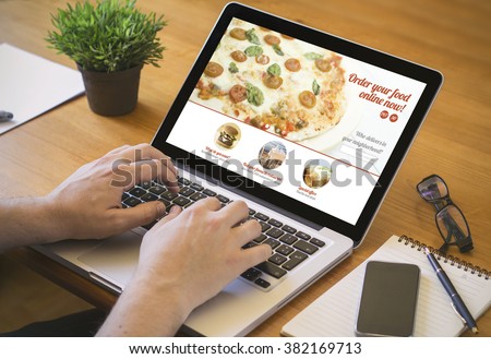 food order concept. Close-up top view of a coolhunter ordering pizza with a laptop. all screen graphics are made up.