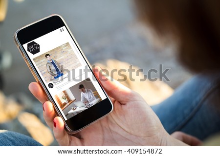 close-up view of young woman with fashion blog on  her mobile phone. All screen graphics are made up.
