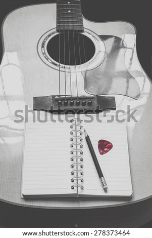 guitar,pencil and scrapbook ,Writing music in black and white tone red guitar pick