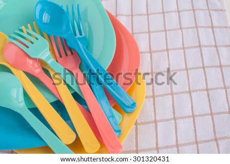 colorful fork ,knife and spoon put on colorful plastic plate at tablecloth