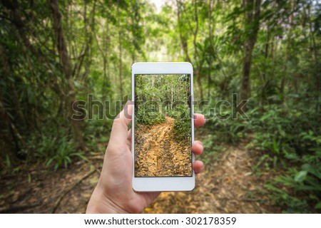 Business conceptual- Focused on left hand holding mobile with Trekking nature  blurred background