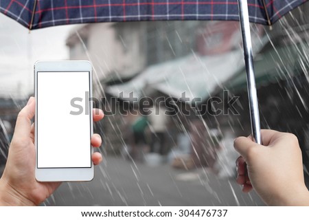Business conceptual- Focused on left hand holding mobile and right hand holding umbrella with rainy background