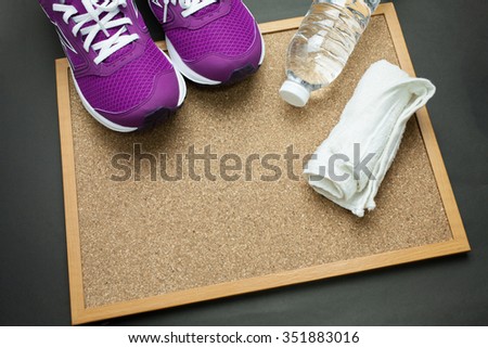 Fitness stuffs: Purple sneaker,towel,and,bottle of water on Pin board with black background