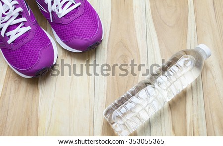 Fitness stuffs: Purple sneaker,bottle of water on wooden background