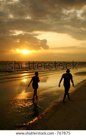 Fit and healthy older couple enjoy sunset walk on a tropical beach
