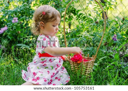 the little beautiful girl collecting flowers in a basket in a garden