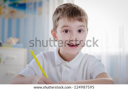 Portrait a cute boy drawing a home with pencil