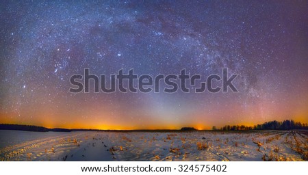 Arch of Milky Way above winter snowy field with zodiacal light and a comet