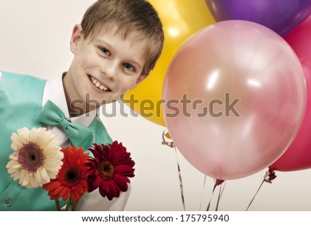 Smiling boy with balloons and  bouquet of flowers as a gift for birthday, mothers day or valentine\'s day