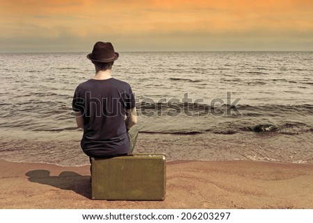 Rest by the sea. The man with a suitcase on a beach in vacation