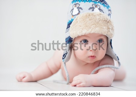 Baby in winter hat lying on the floor