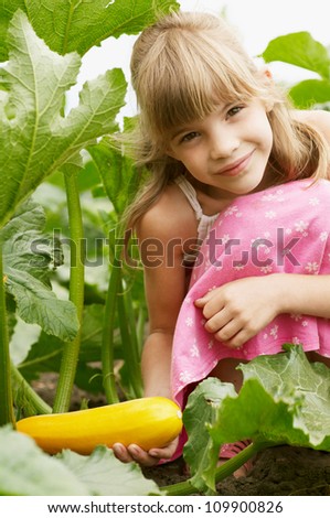 The young girl is in the garden and holding the squash