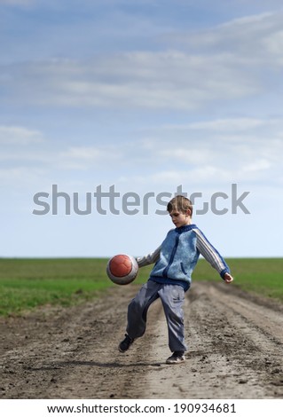 boy playing with a ball on the mud road