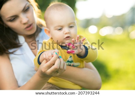 child learns a little flower in the hands of mother