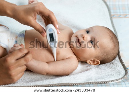 mother measures the temperature of a smiling child