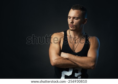 man on a black background with his arms crossed looking sideways
