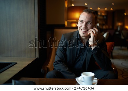 Businessman in a restaurant having fun talking on the phone