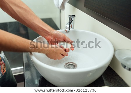 man cleans hands in the beautiful bathroom  with soap