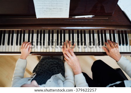 a music teacher with the pupil at the lesson piano, top view