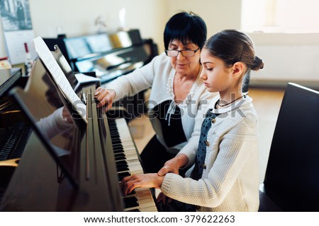 a music teacher with the pupil at the lesson piano