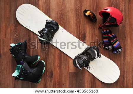 set of snowboard equipment  boots, helmet, gloves and mask on a wooden floor
