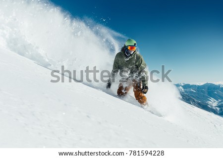 male snowboarder curved and brakes spraying loose deep snow on the freeride slope