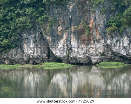This is a rock wall eaten away by the forces of nature reflected in the river. Taken in Guilin China.